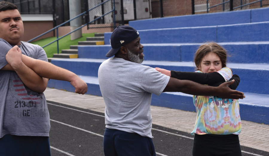  Students at track and field practice stretch their shoulders. 
